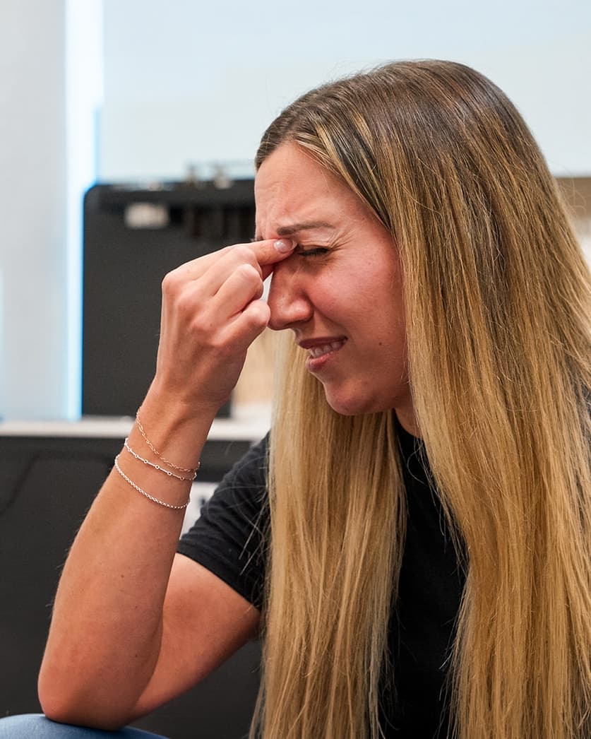 Woman pinching the bridge of her nose from sinus pain and pressure caused by sinusitis